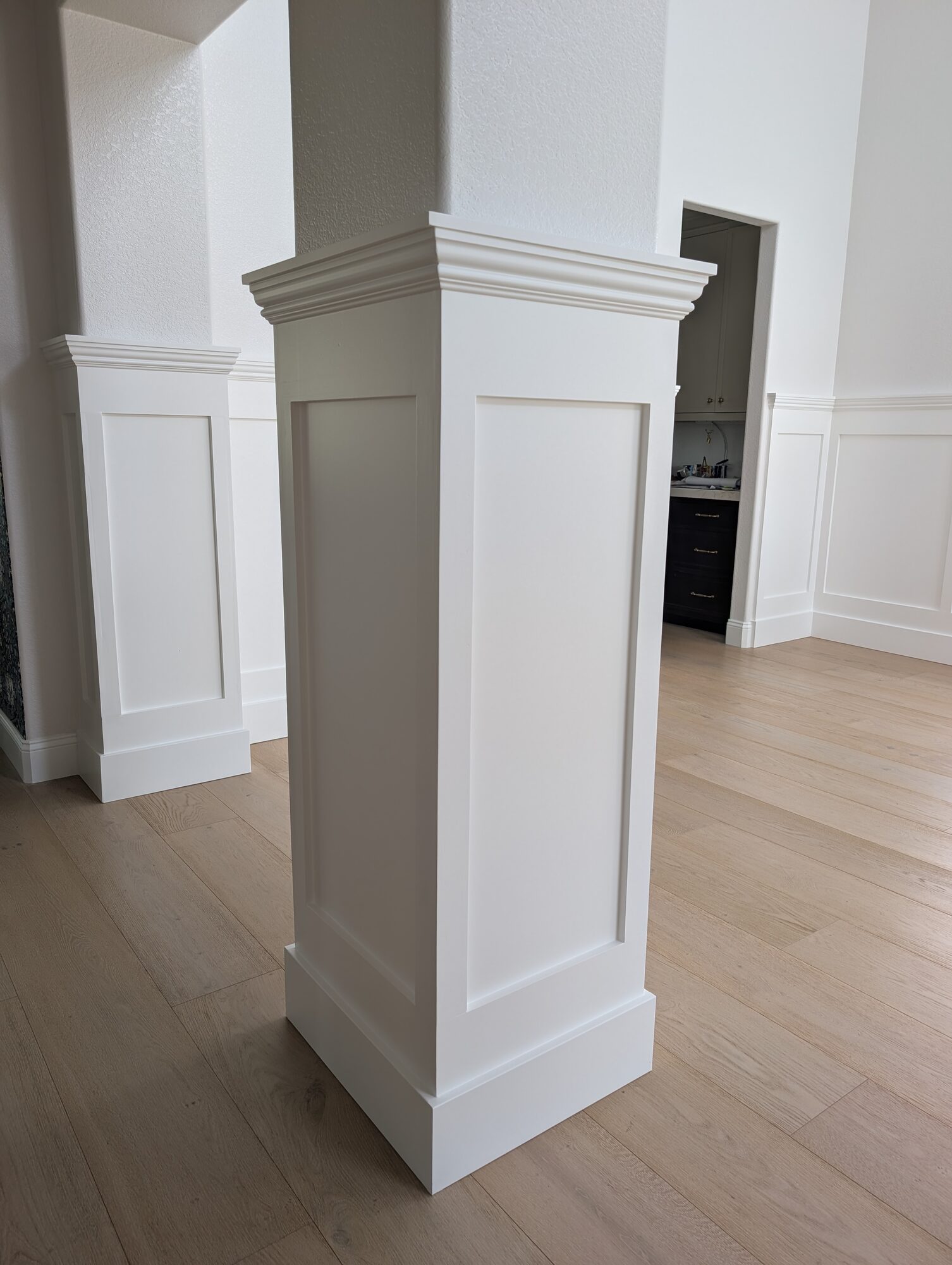 Close-up of paneled column wrap with tall plinth and molded cap, paint-grade wainscoting, Rancho Cucamonga