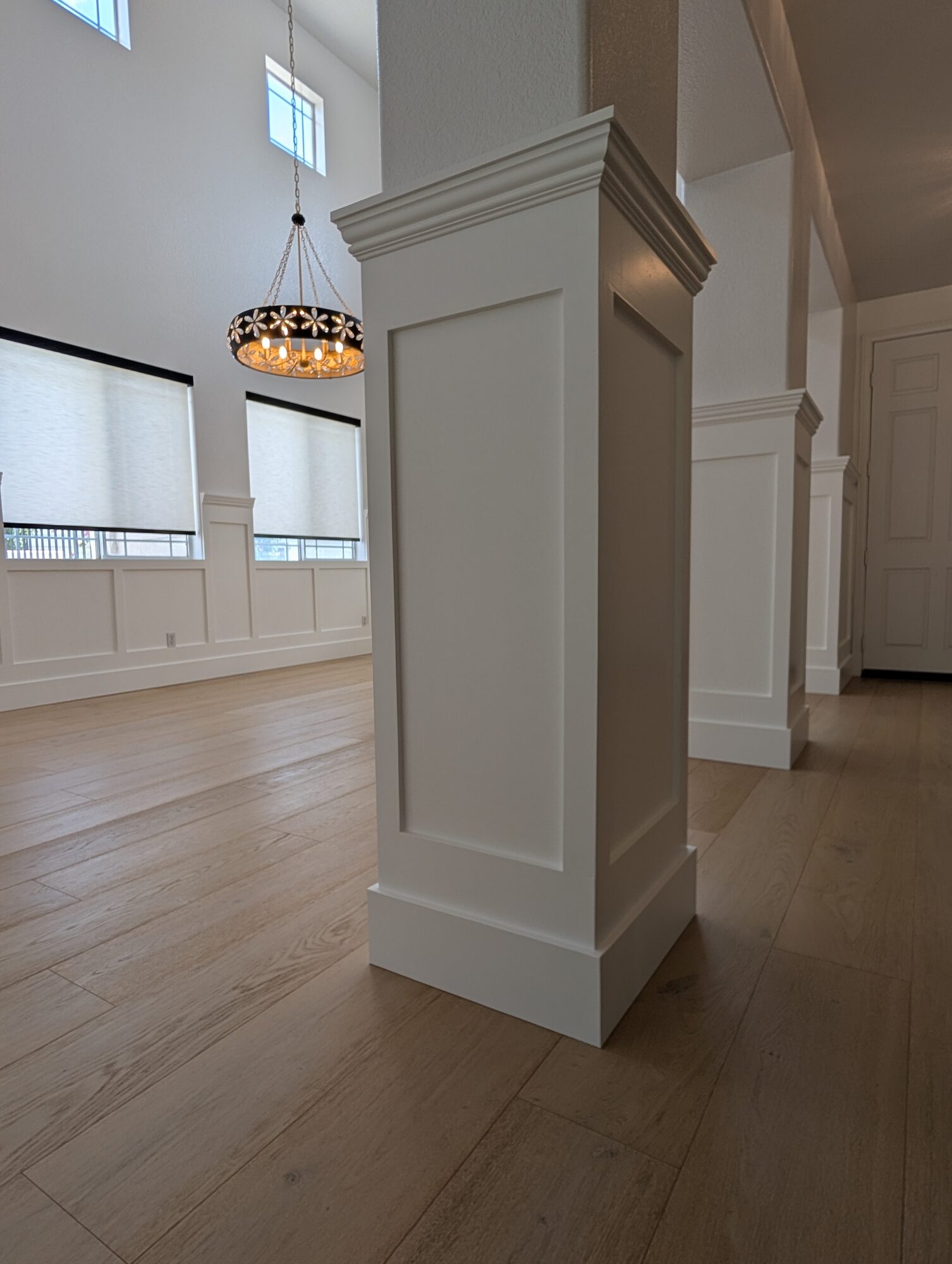 Low angle of paneled column in a sunlit dining room with chandelier, Rancho Cucamonga wainscoting