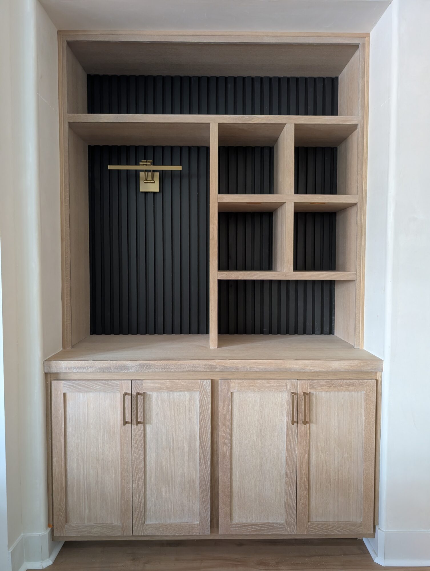 Finished oak built-in with four Shaker doors, brass pulls, upper cubbies and black slat backing, Winchester CA