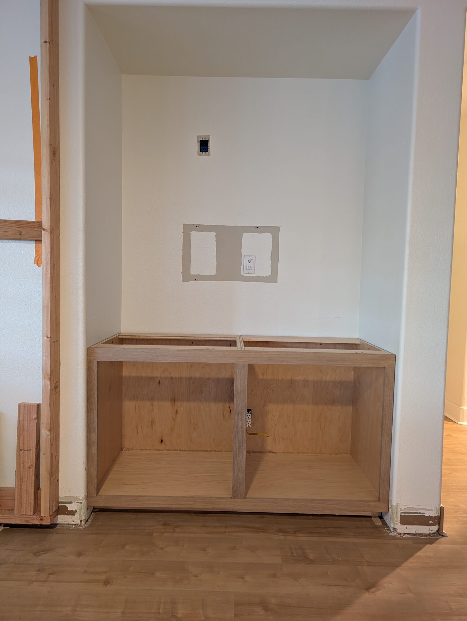 Plywood base cabinet carcass set and leveled in the alcove next to the fireplace opening, Winchester CA