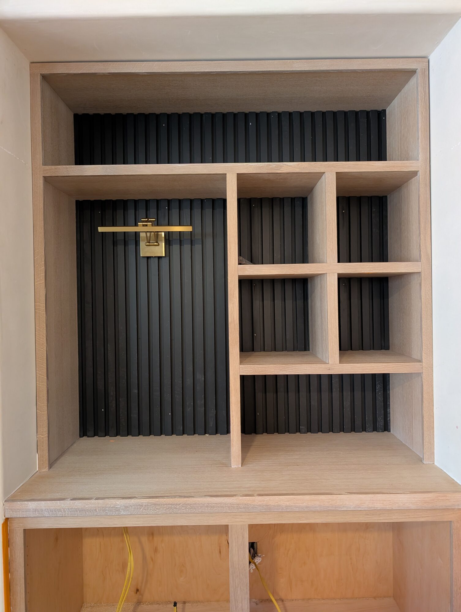 Black poplar slat backing behind the oak cubbies with the antique brass picture light mounted, Winchester CA