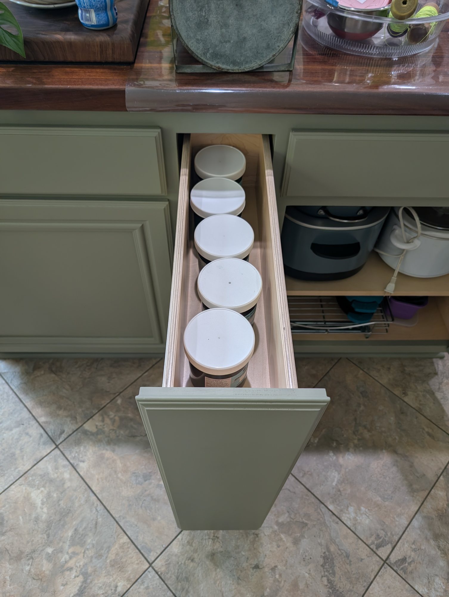 Top view of a narrow kitchen island pull-out organizer holding a row of jars in Menifee, CA