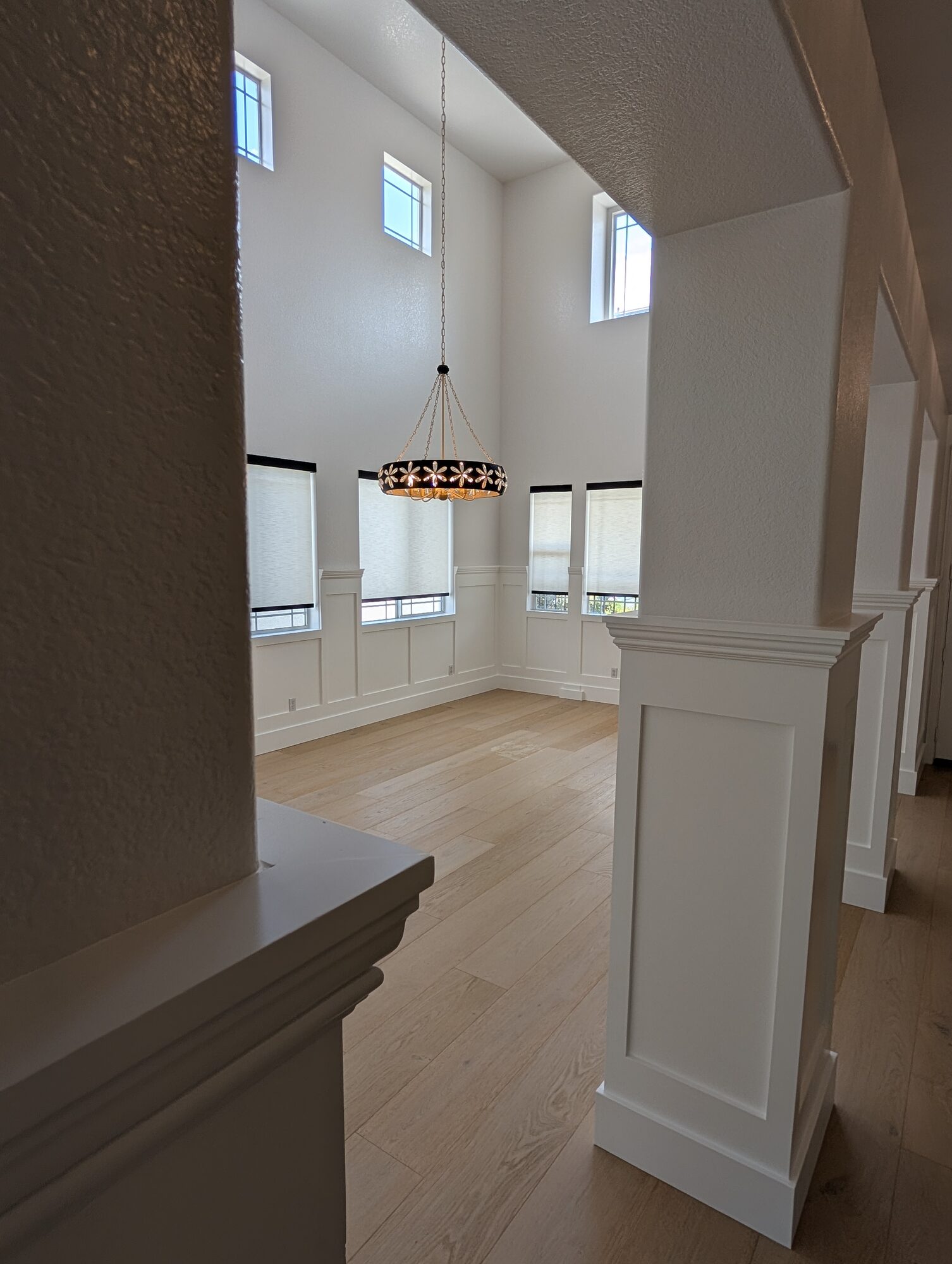 View past paneled column into sunlit dining room with wainscoting and high windows, Rancho Cucamonga
