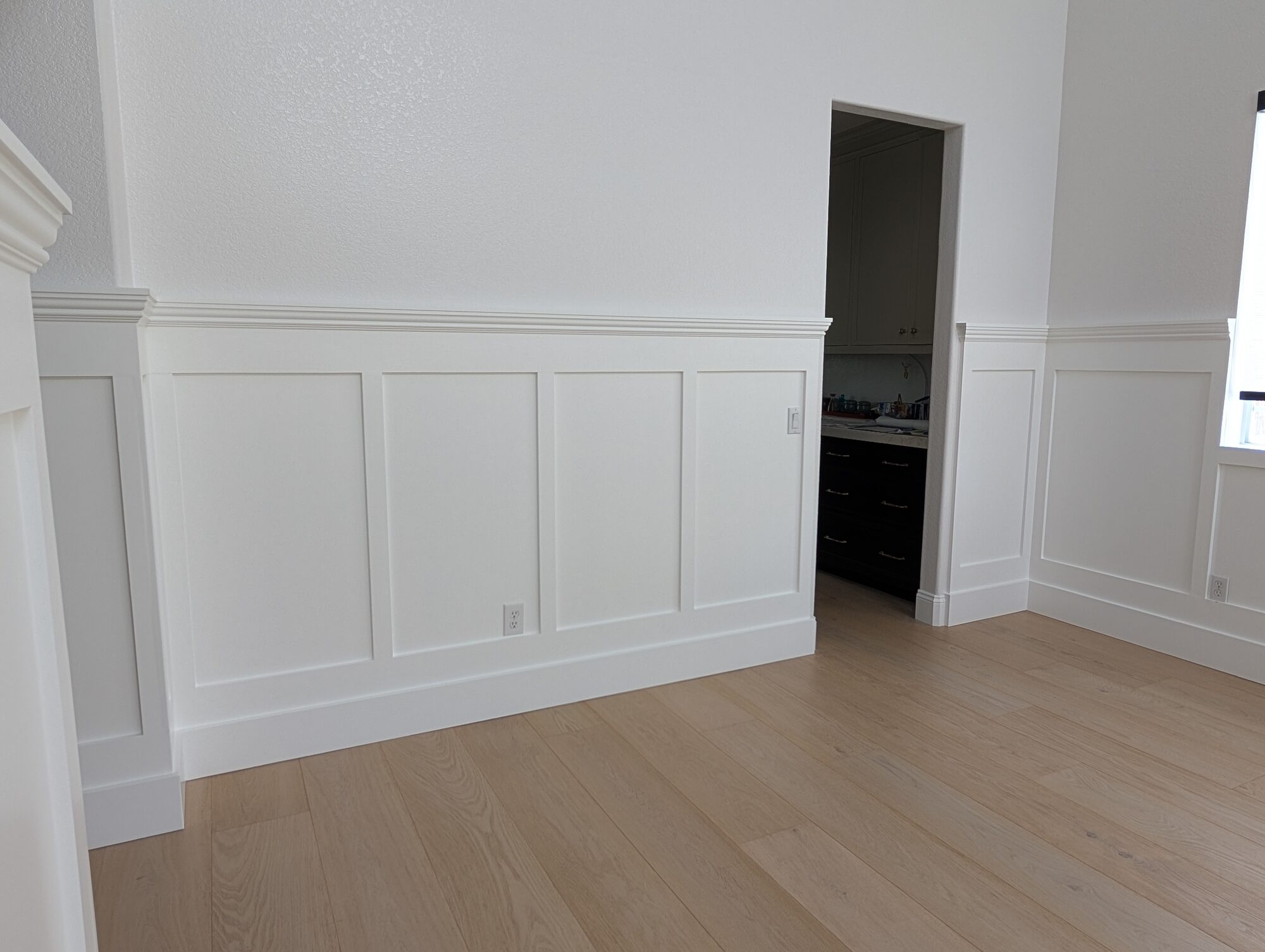 White panel wainscoting with pediment cap leading to pantry doorway in Rancho Cucamonga dining room