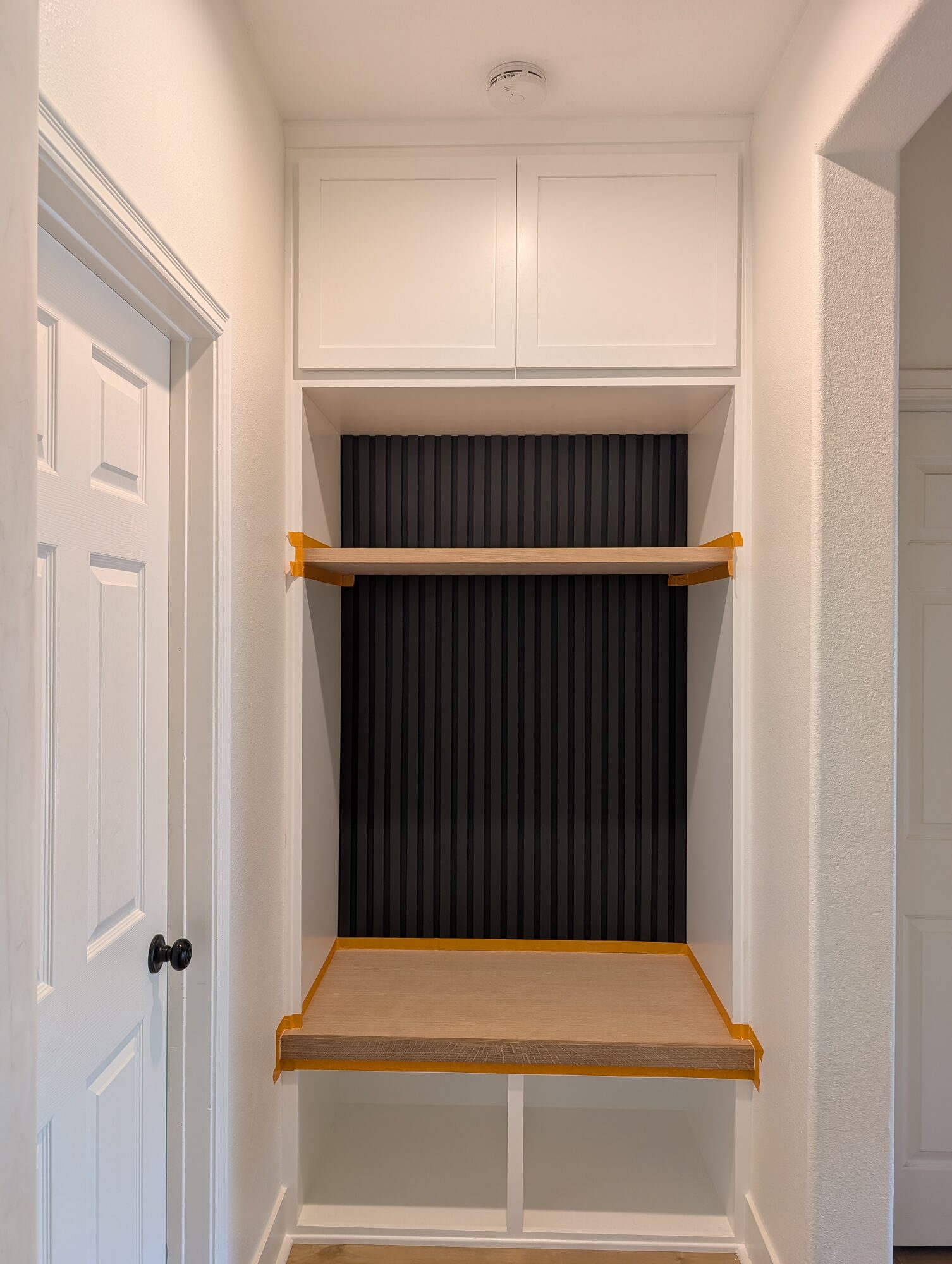 Black slats run full height with orange tape protecting the white oak bench and shelf, Winchester CA